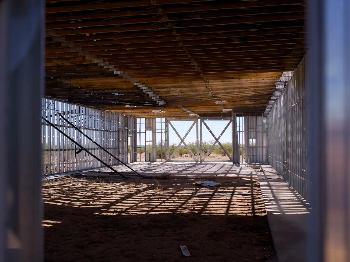 A steel-framed commercial building under construction, open to the desert